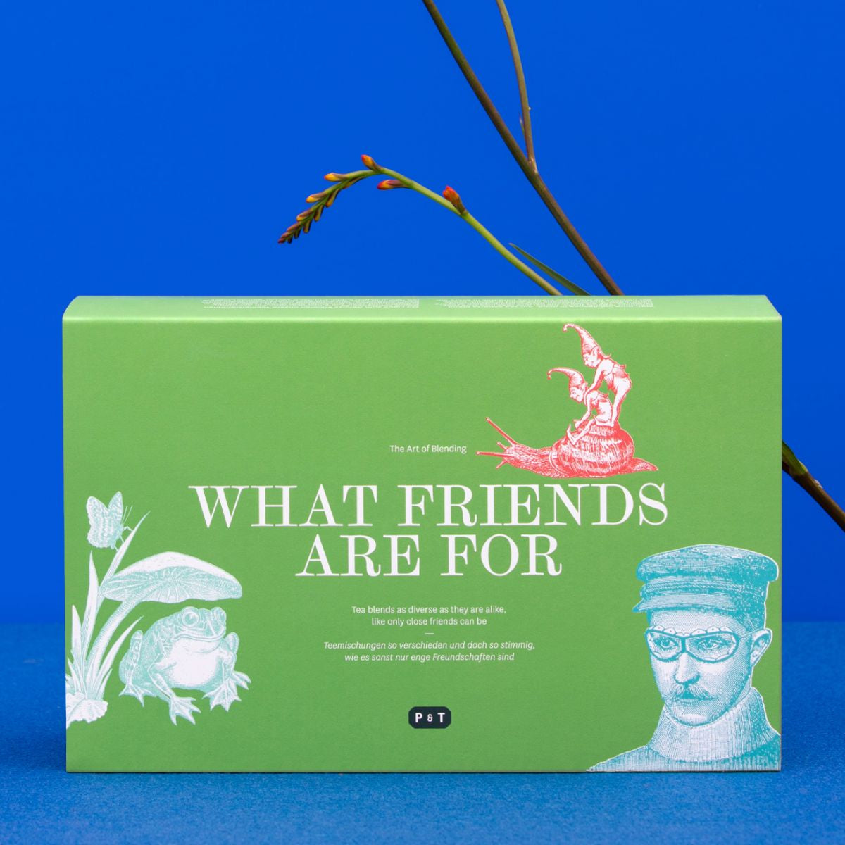 Grüne Teeverpackung 'The Art of Blending' mit Vintage-Illustrationen und orange-roten Blumen.
